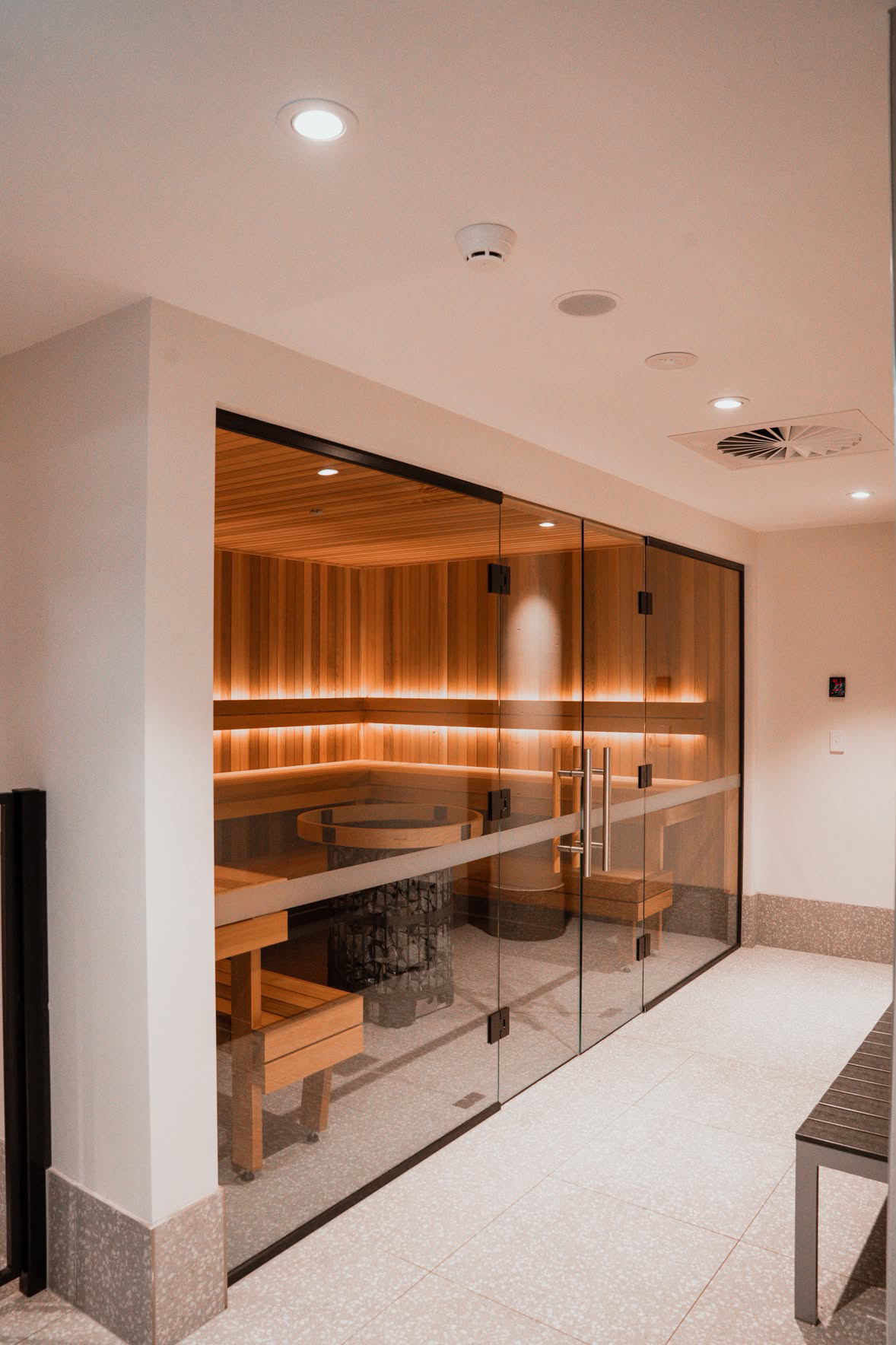 Glass-fronted indoor sauna with softly illuminated timber benches